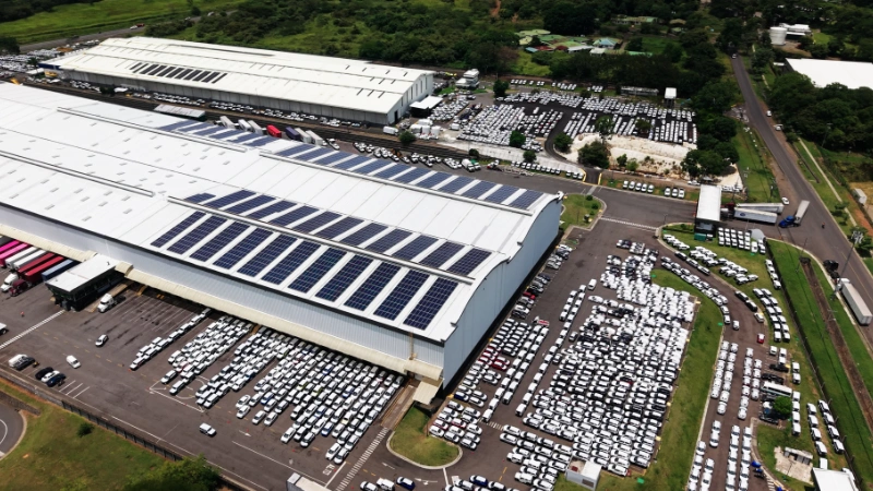 Gran nave industrial con sistema de paneles solares en la cubierta y estacionamiento contiguo.
